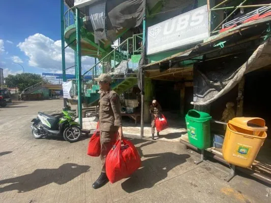 Petugas Satpol PP Kota Tangerang saat membantu pedagang memindahkan barang dagangan ke tempat relokasi. (Istimewa)