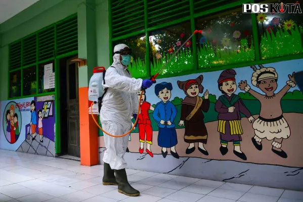 Petugas menyemprotkan disinfektan di sekolah. (foto: poskota.co.id/fernando toga)