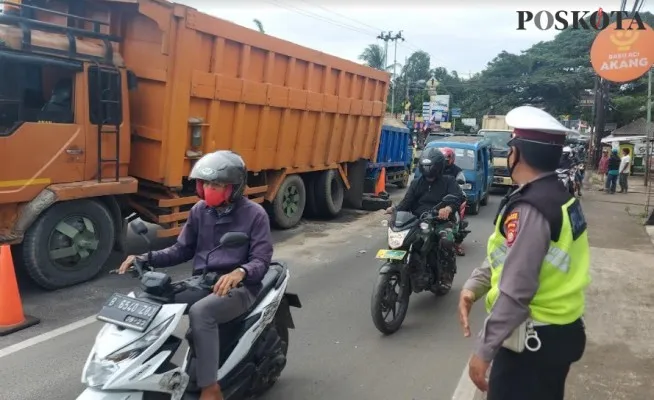 Petugas Polantas Polsek Bojongsari Aiptu Syaiful melakukan pengaturan lalu Lintas di lokasi truk dum patah as mengurai kemacetan (angga)