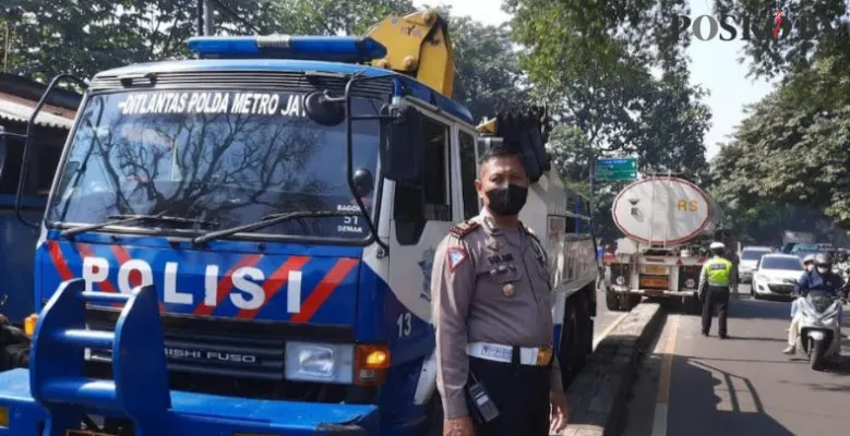 Kanit Lantas Polsek Cimanggis AKP Sulani dibantu anggota melakukan pengamanan penderekan trailer yang menabrak sparator Jalan Raya Bogor. (Angga)