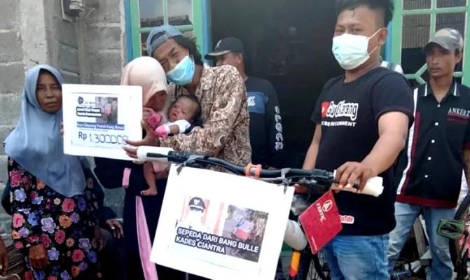 Perwakilan dari Roni (31) saat melakukan simbolik penyerahan uang dan sepeda pada kang Emon di kediamannya, di Sukawangi, Kabupaten Bekasi. (Foto/ihsan)