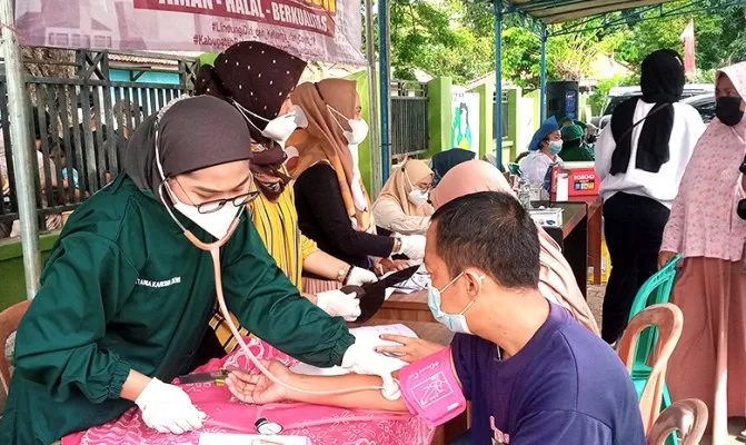 Suasana lokasi vaksinasi di kantor desa Cipayung, Cikarang Timur, Kabupaten Bekasi, peserta mendapatkan bendera merah putih dari petugas. (Foto/ihsan)