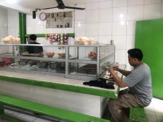 Salah seorang pembeli saat menyantap hidangan di warteg di kawasan Kota Bekasi.(Poskota.co.id/Ihsan Fahmi)