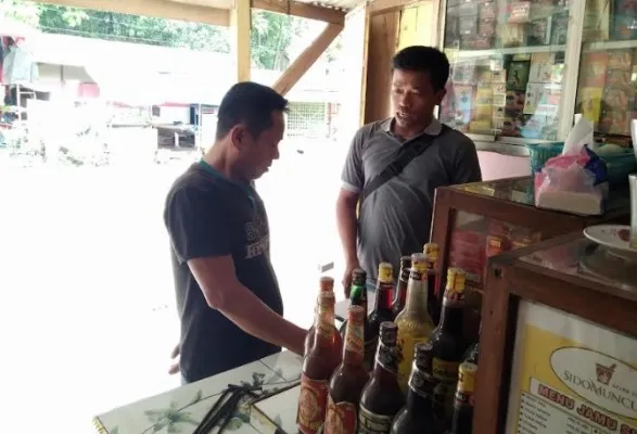 Petugas Polsek Maniis menyita belasan botol miras dijual di kios jamu diwilayahnya. (dadan)